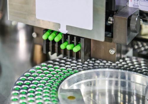 A machine is making green capsules in a factory.