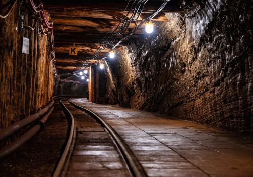 Tunnel in a mine with tracks, dimly lit, curved path leading into the darkness.