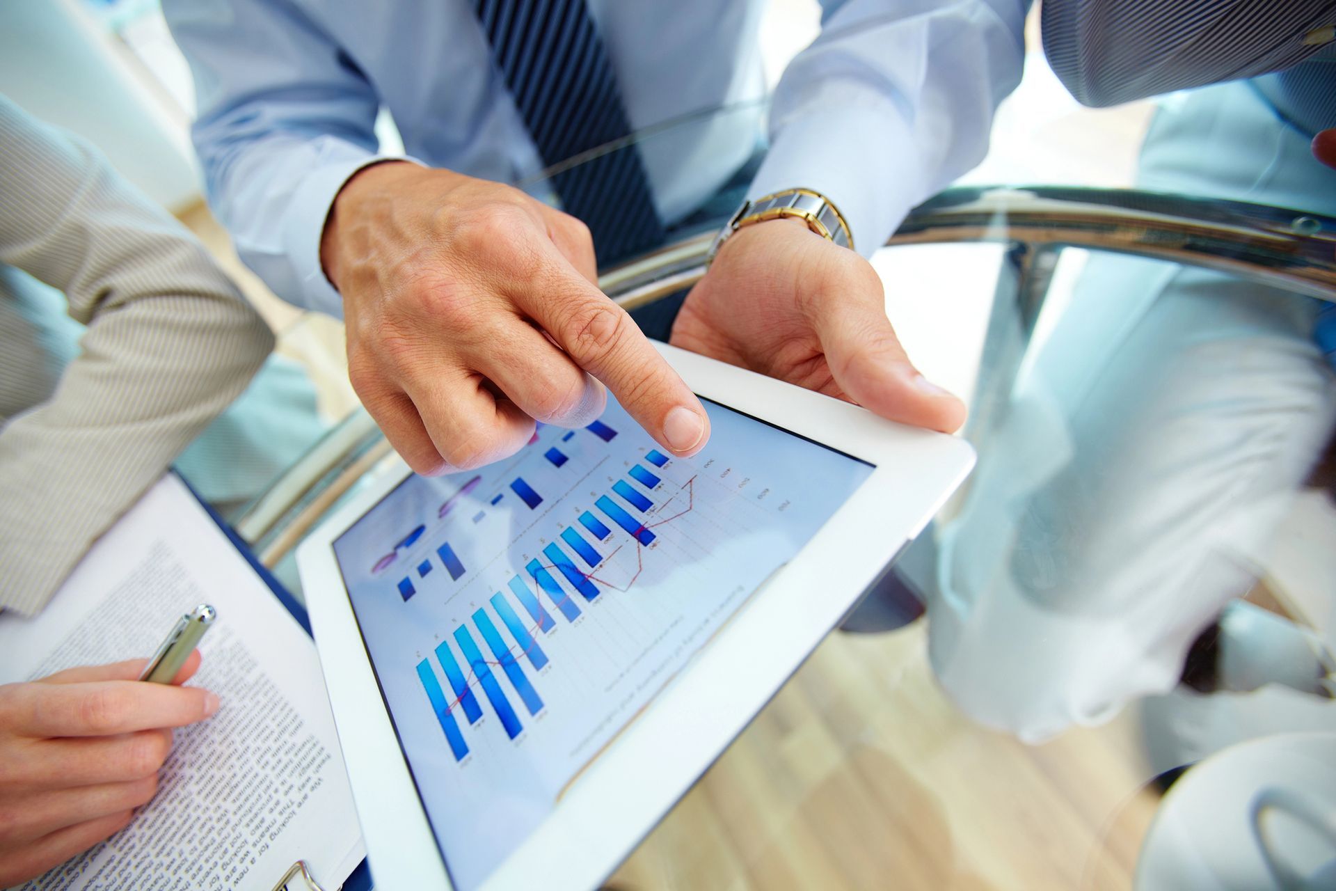 A man is pointing at a tablet with a graph on it