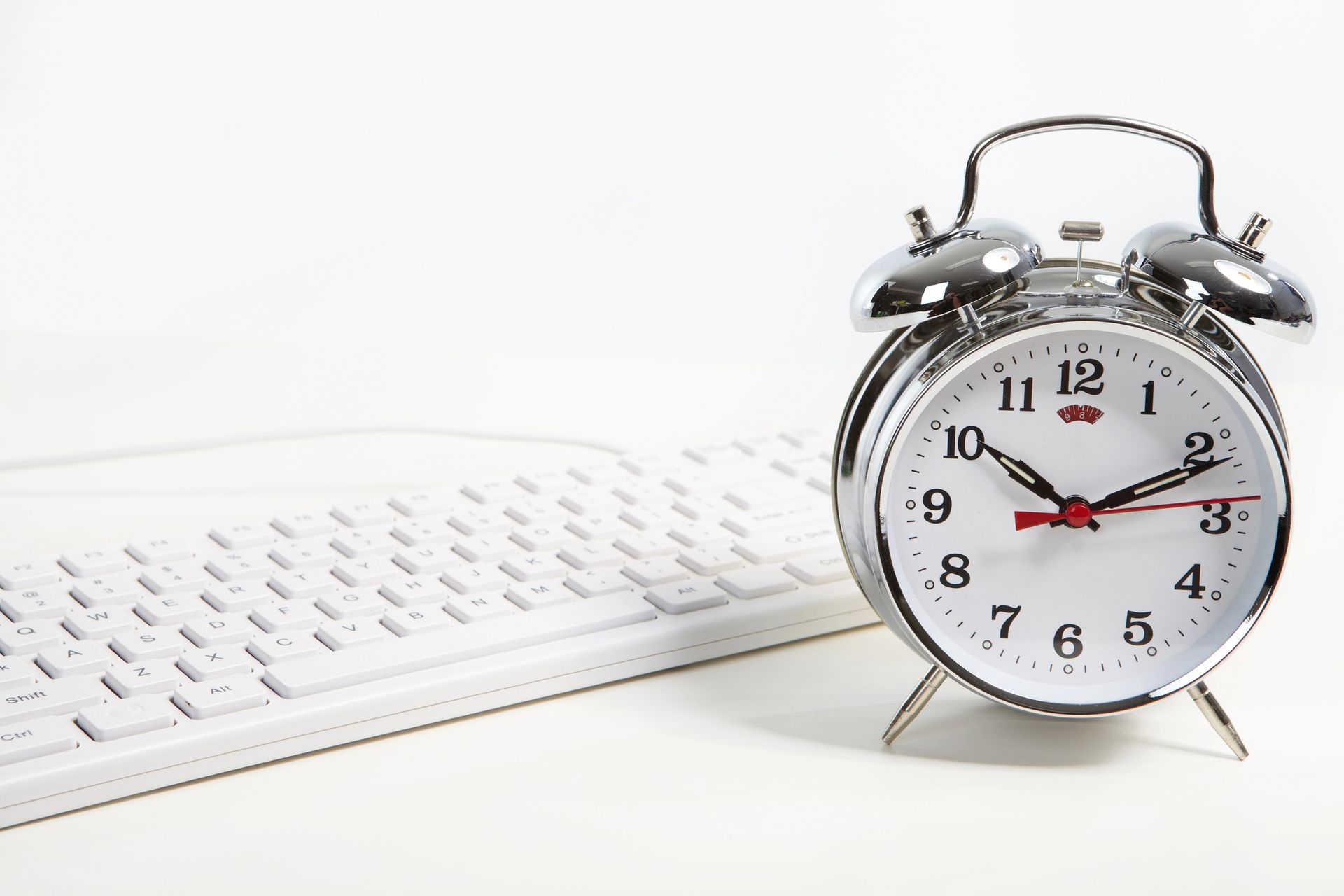 An alarm clock sitting on top of a white keyboard