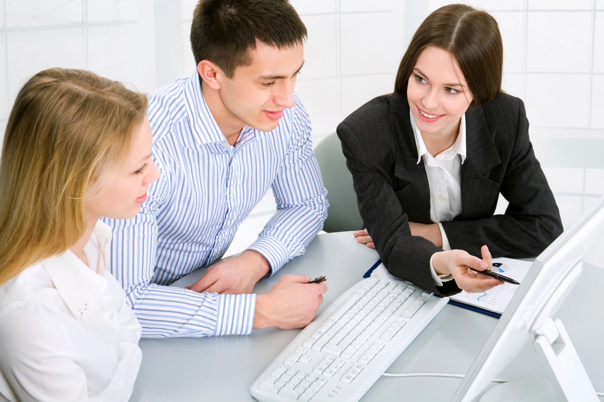 A man and two women are looking at a computer screen