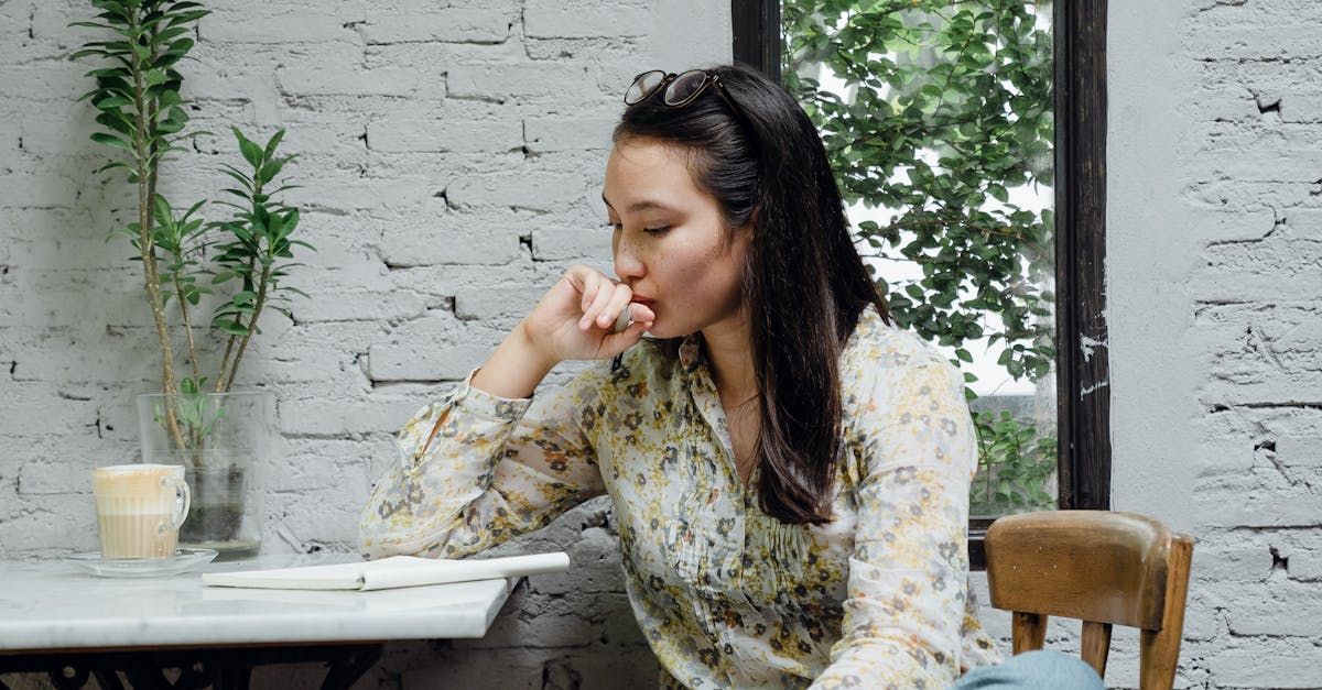 A woman is sitting at a table in front of a window.