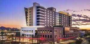 Modern hotel building at dusk with illuminated windows and a city street in front