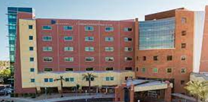 Multi-story brick and glass building with a courtyard entrance under a blue sky