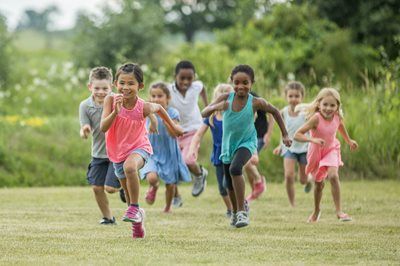 Children running and smiling across a grassy field outdoors