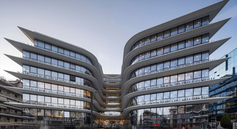 Moderno edificio per uffici con balconi curvi in ​​cemento, simili ad ali, e grandi finestre in vetro.