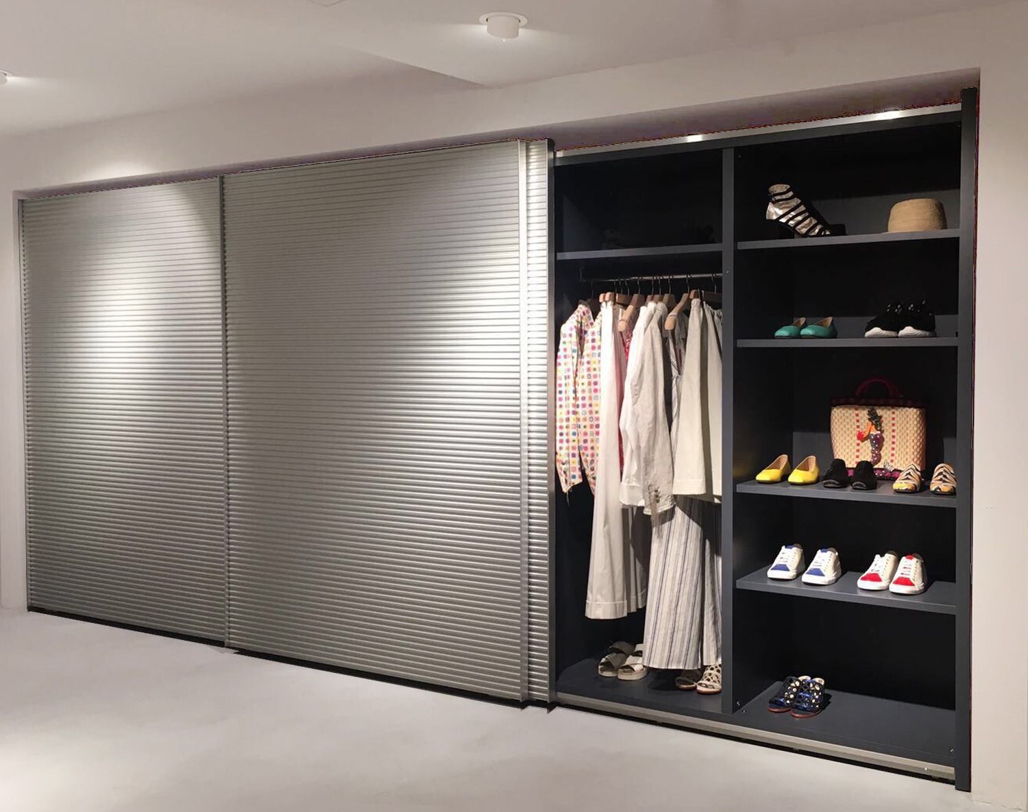 Armadio con ante scorrevoli testurizzate che si aprono per rivelare abiti appesi e ripiani con scarpe e accessori.