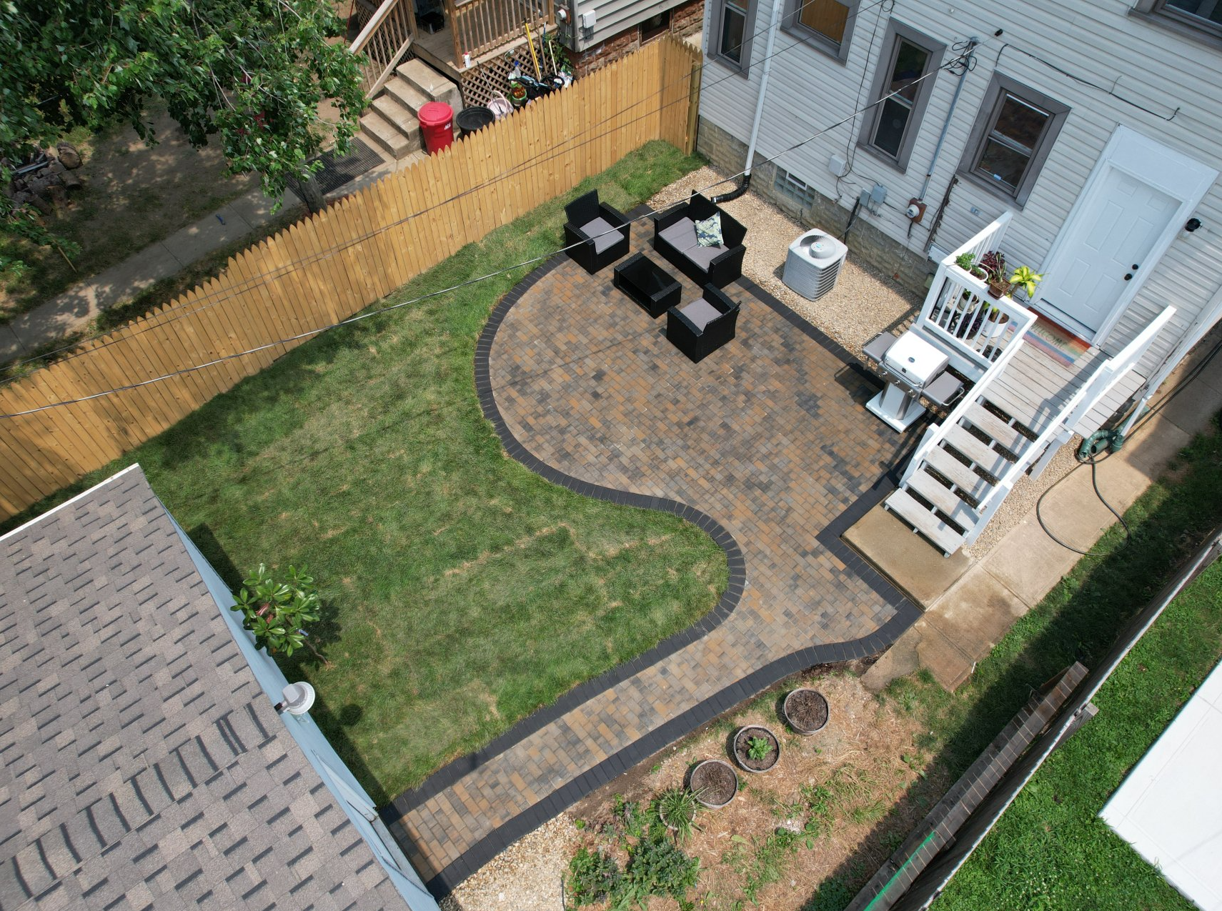 Backyard patio with curved stone path, lawn, black outdoor furniture, and white house steps