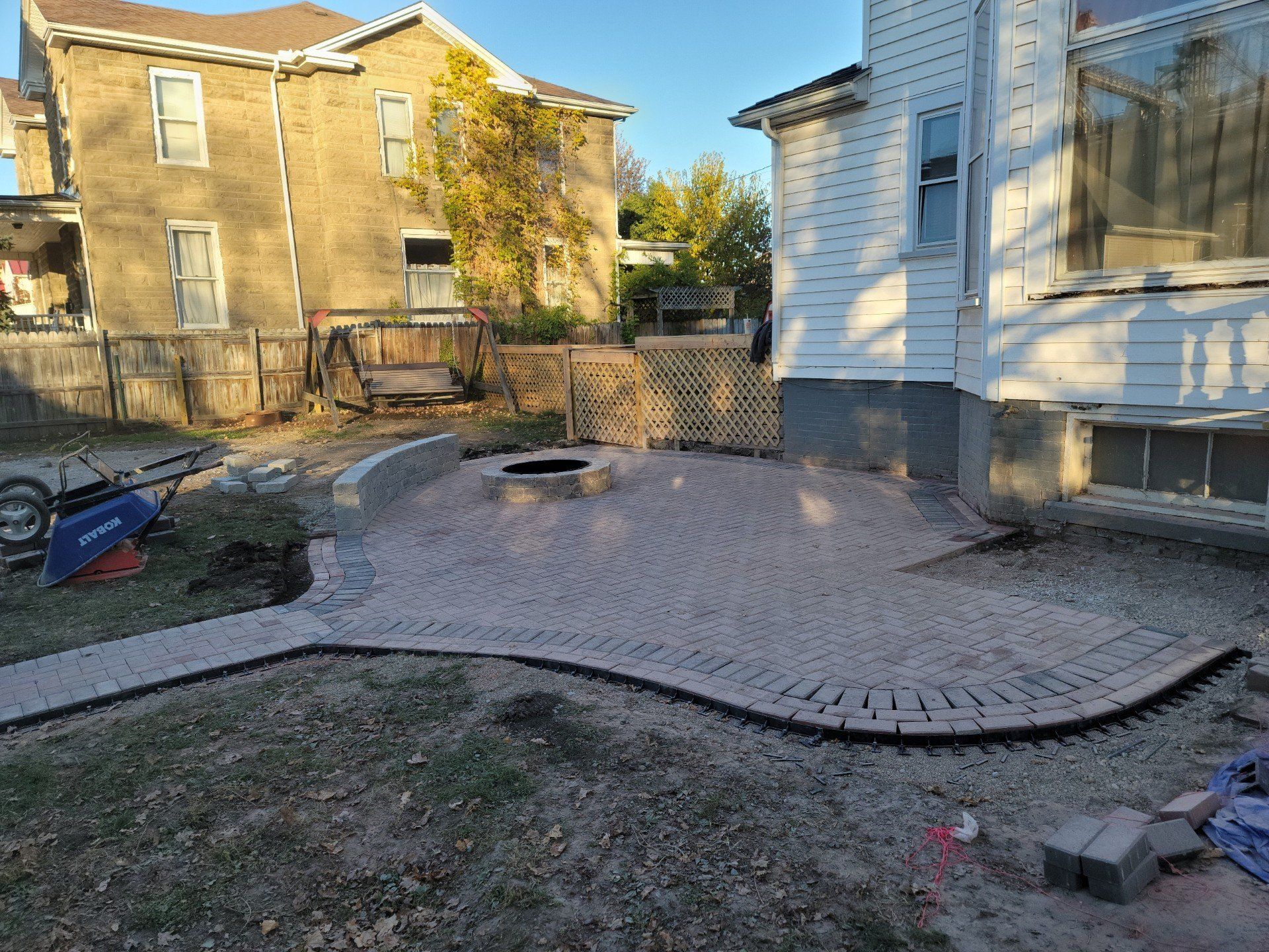 Backyard with a gravel patio, raised lawn edges, and neighboring houses in the background