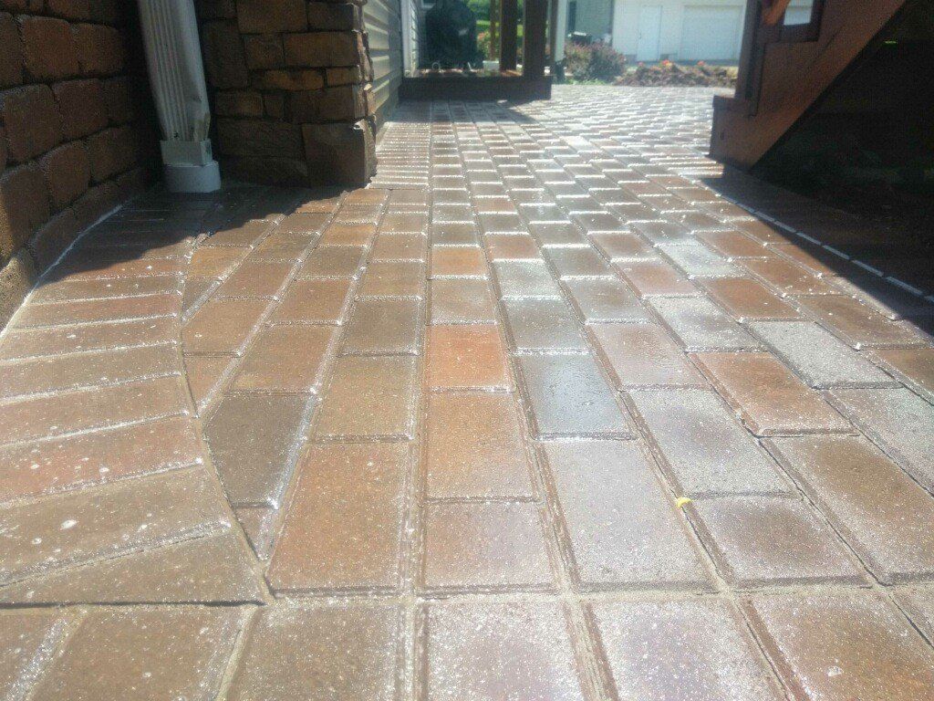 Sunlit brick patio with wet, reflective pavers between stone walls and a doorway