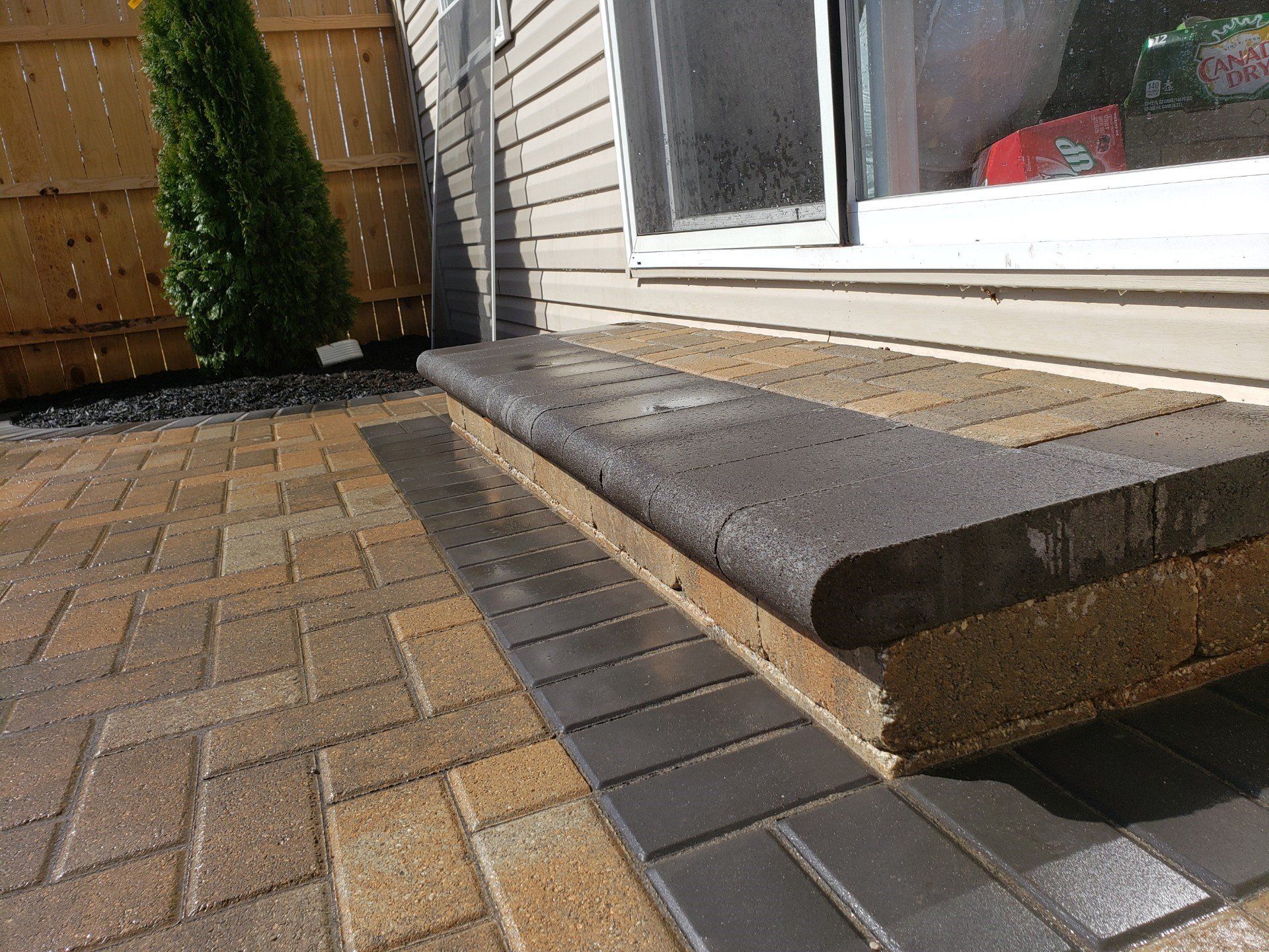 Brick patio beside a house step and sliding glass door, with a dark doorstep edge.