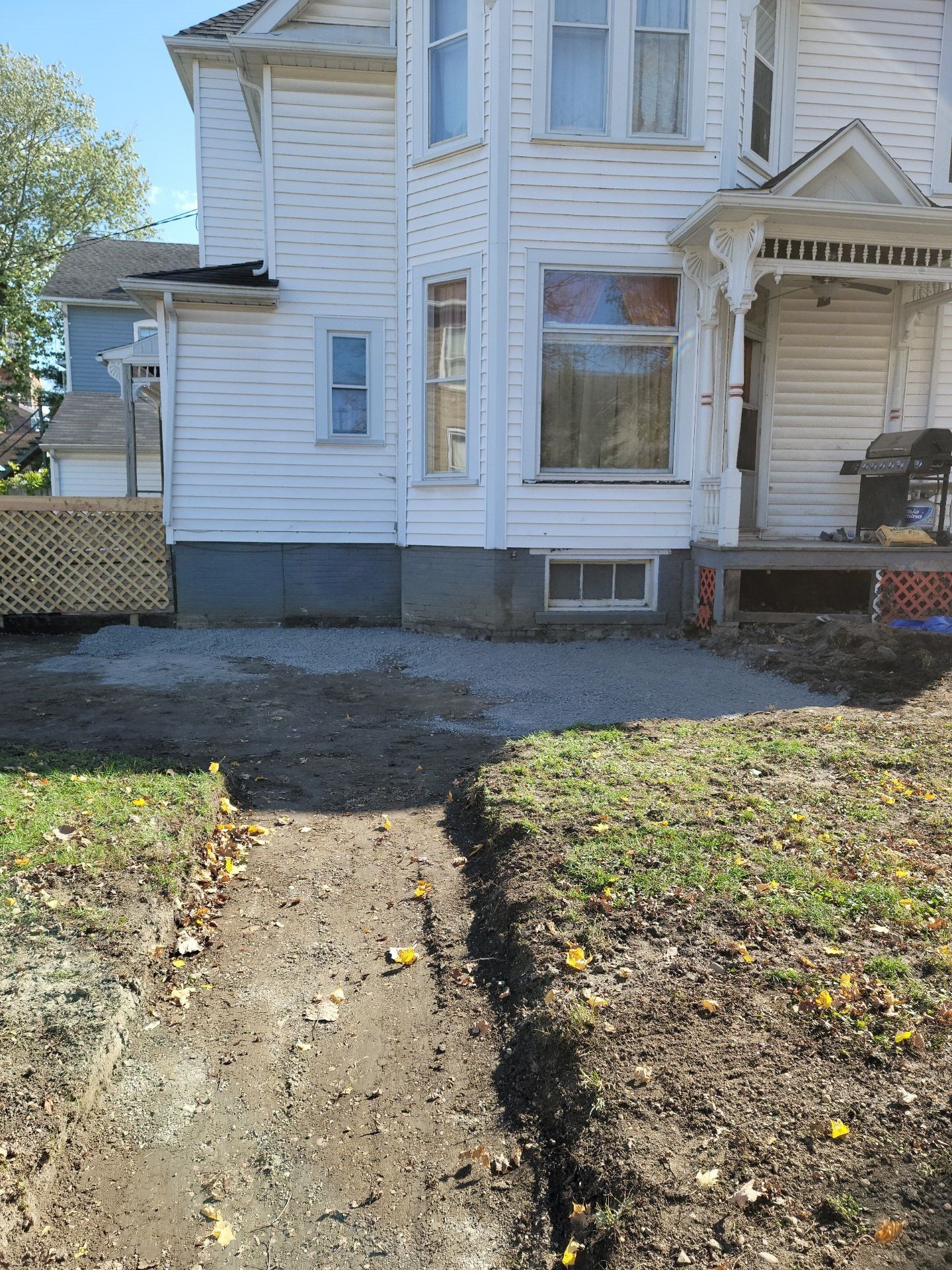 White two-story house with a front porch and a cracked walkway through a patchy yard.