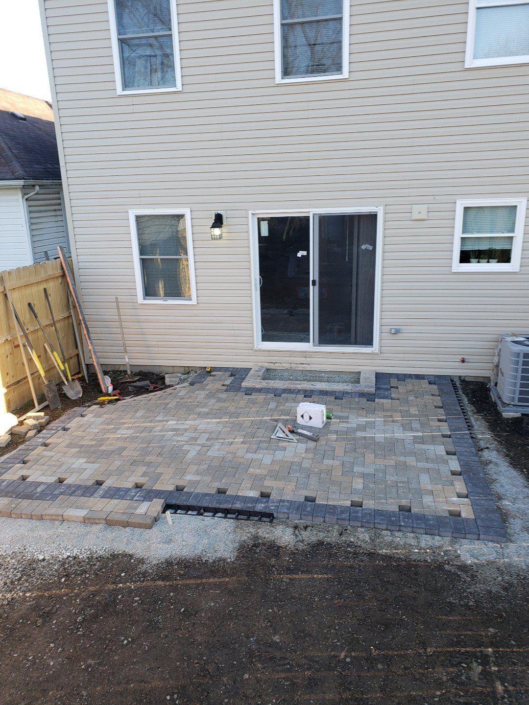 Backyard patio with paver stones and sliding glass doors on a beige house