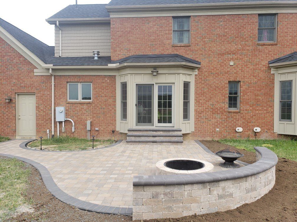 Back patio with stone pavers, circular fire pit, and brick house with French doors