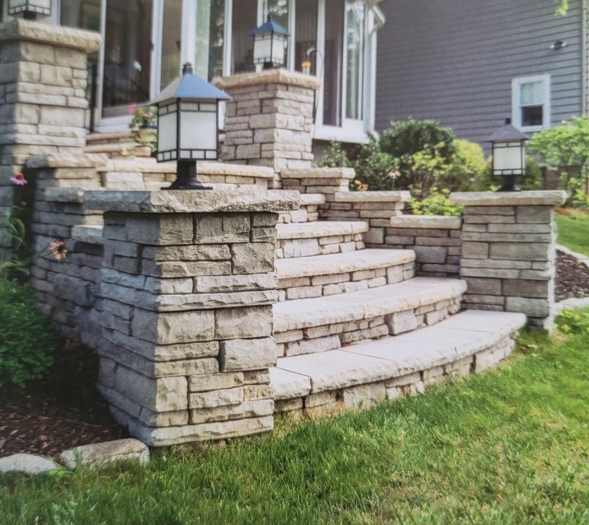 Stone front steps with a lantern, leading up to a house with a landscaped lawn and porch.