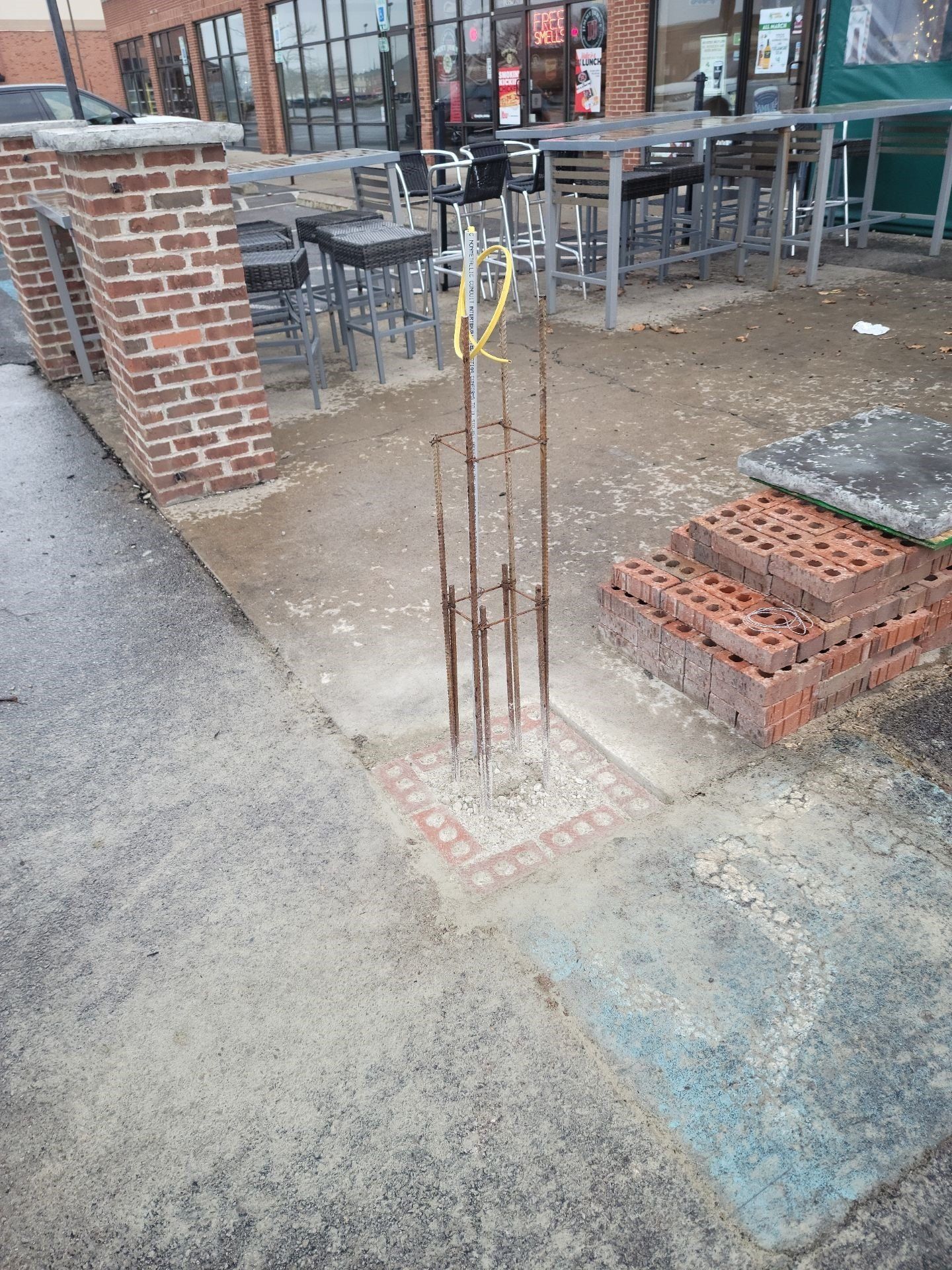 Construction site with exposed rebar and bricks beside a building entrance