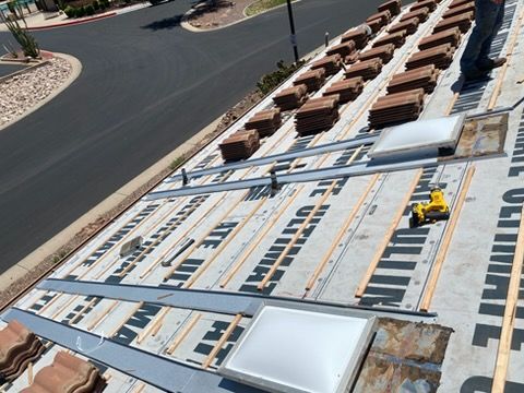Solar panels being installed on a flat roof beside a curved street, with workers and equipment visible