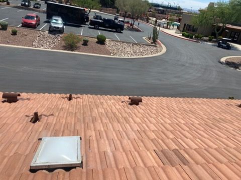 View from a terracotta roof over a parking lot with cars and a curved driveway on a sunny day