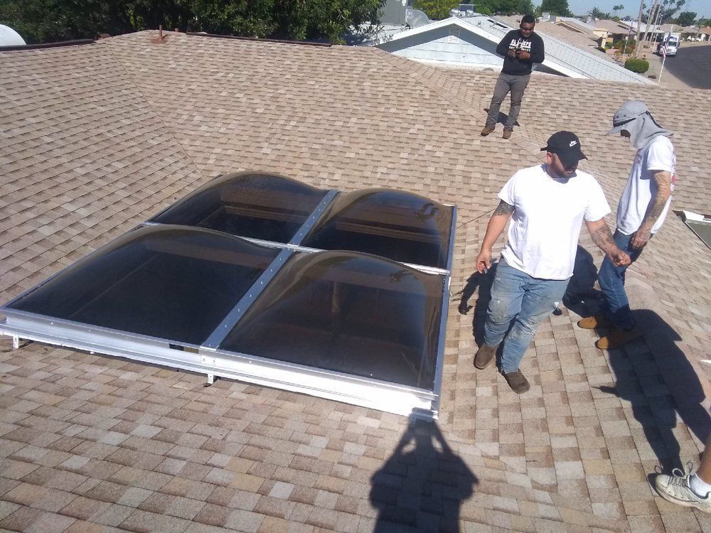 Workers installing a skylight on a residential roof, with a dog nearby.