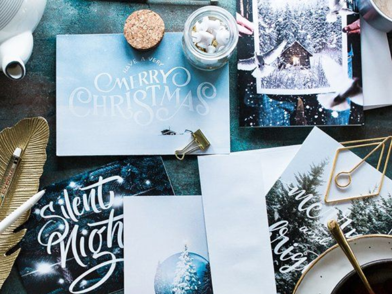 Des cartes et des articles de Noël disposés sur une table, notamment des cartes « Joyeux Noël » et « Douce nuit ».