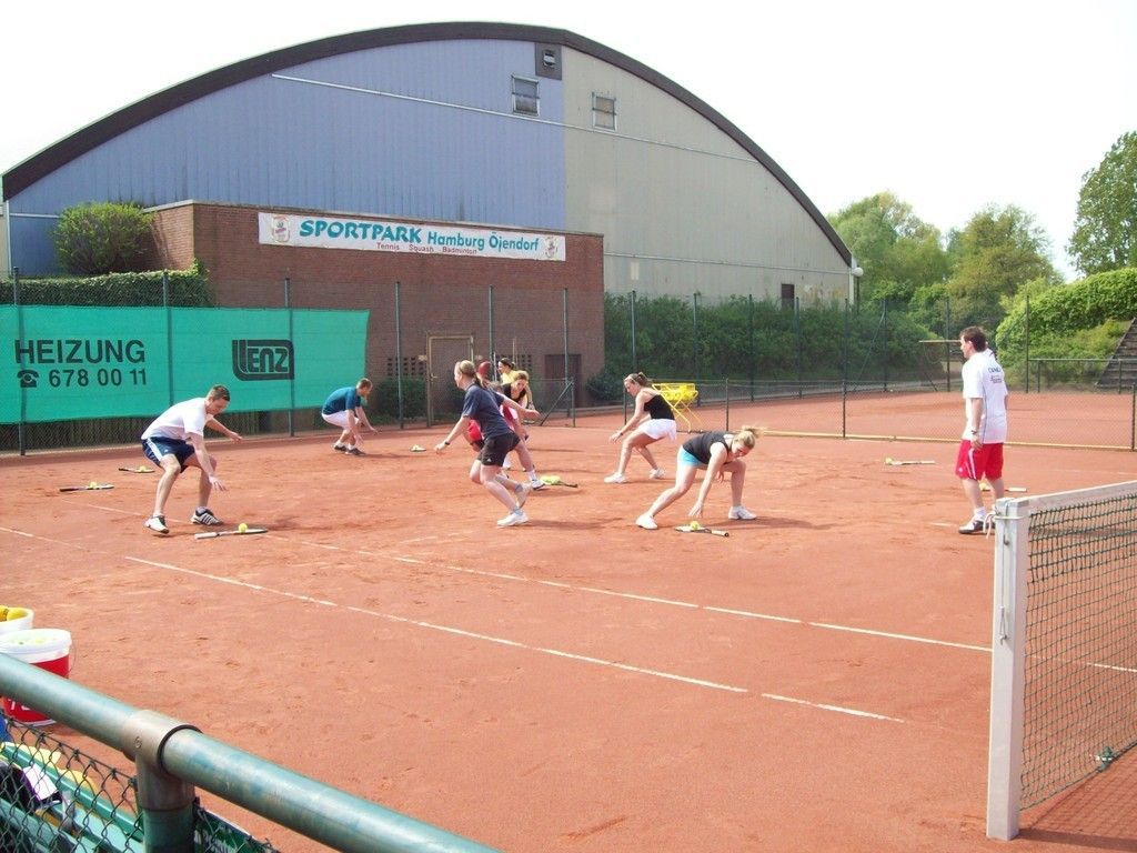Eine Gruppe von Menschen auf einem Tennisplatz mit einem Schild mit der Aufschrift „Heizung“