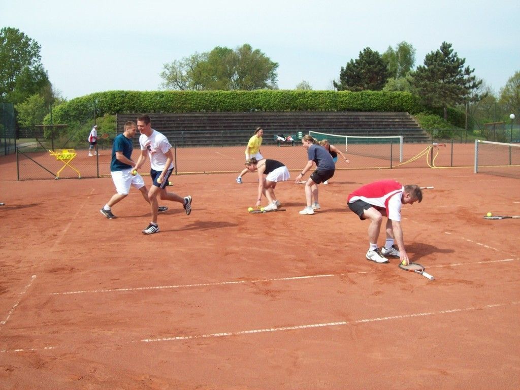 Eine Gruppe von Menschen spielt Tennis auf einem Tennisplatz