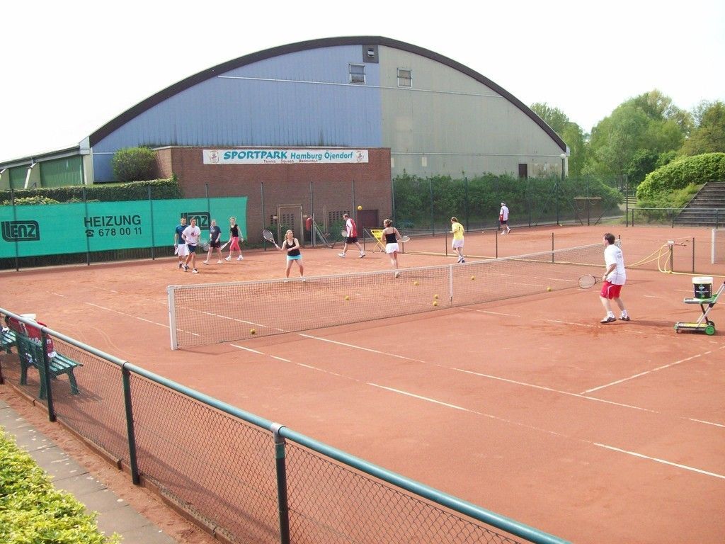 Eine Gruppe von Menschen spielt Tennis auf einem Tennisplatz