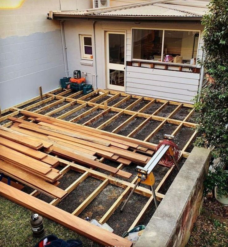 A wooden deck is being built in the backyard of a house