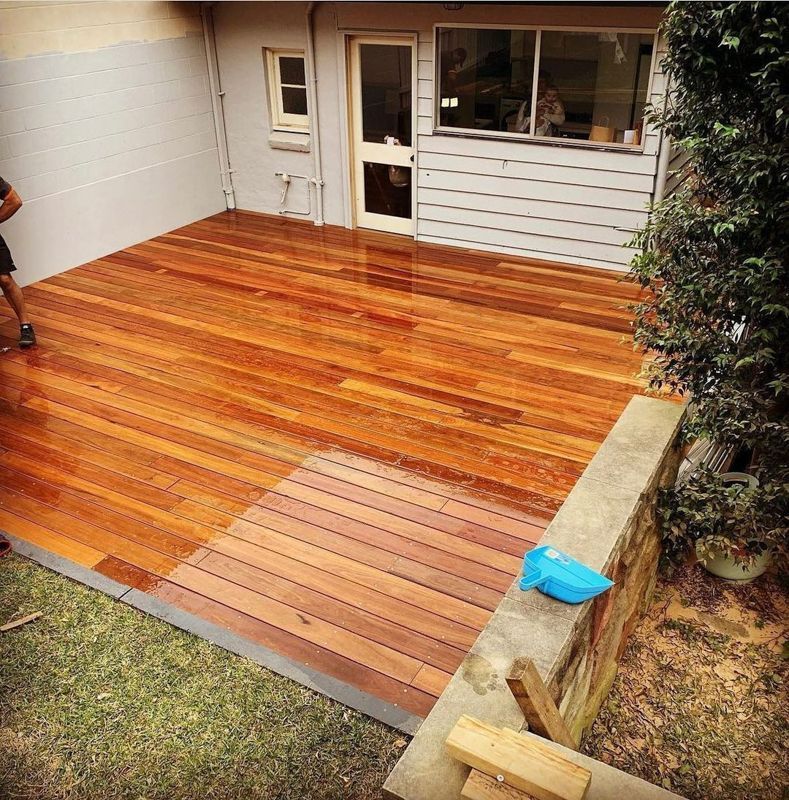 A man is standing on a wooden deck in front of a house
