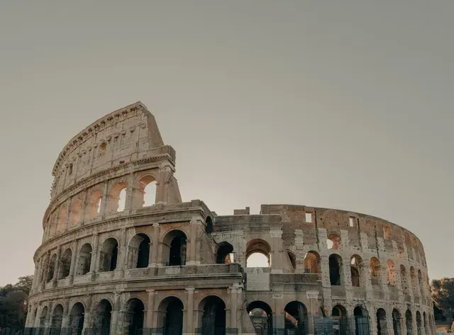 Colosseum in Rome, Italy, at sunset; weathered stone structure with arches and open sky.
