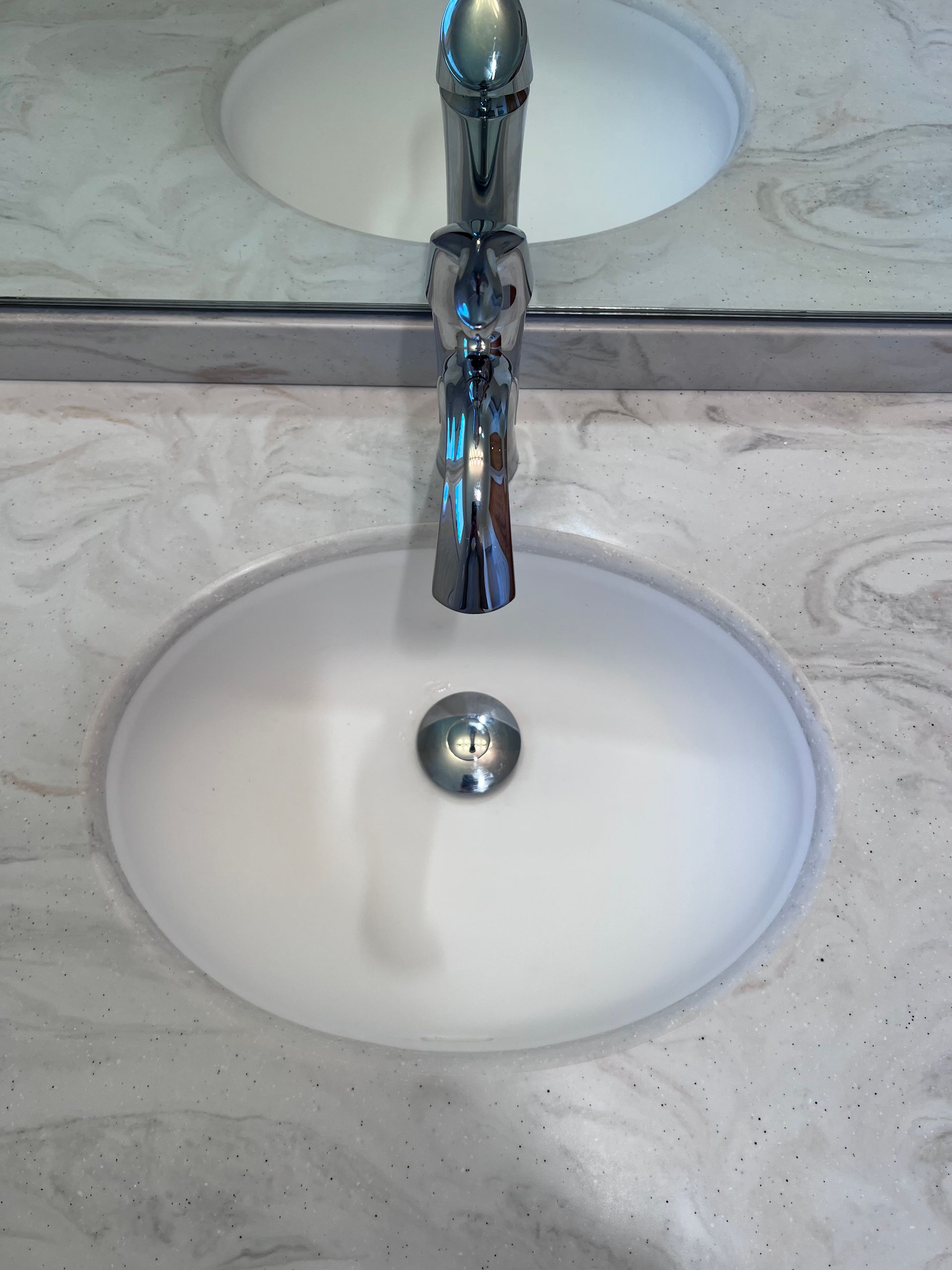 Two white vessel sinks with a chrome faucet on a light marble countertop