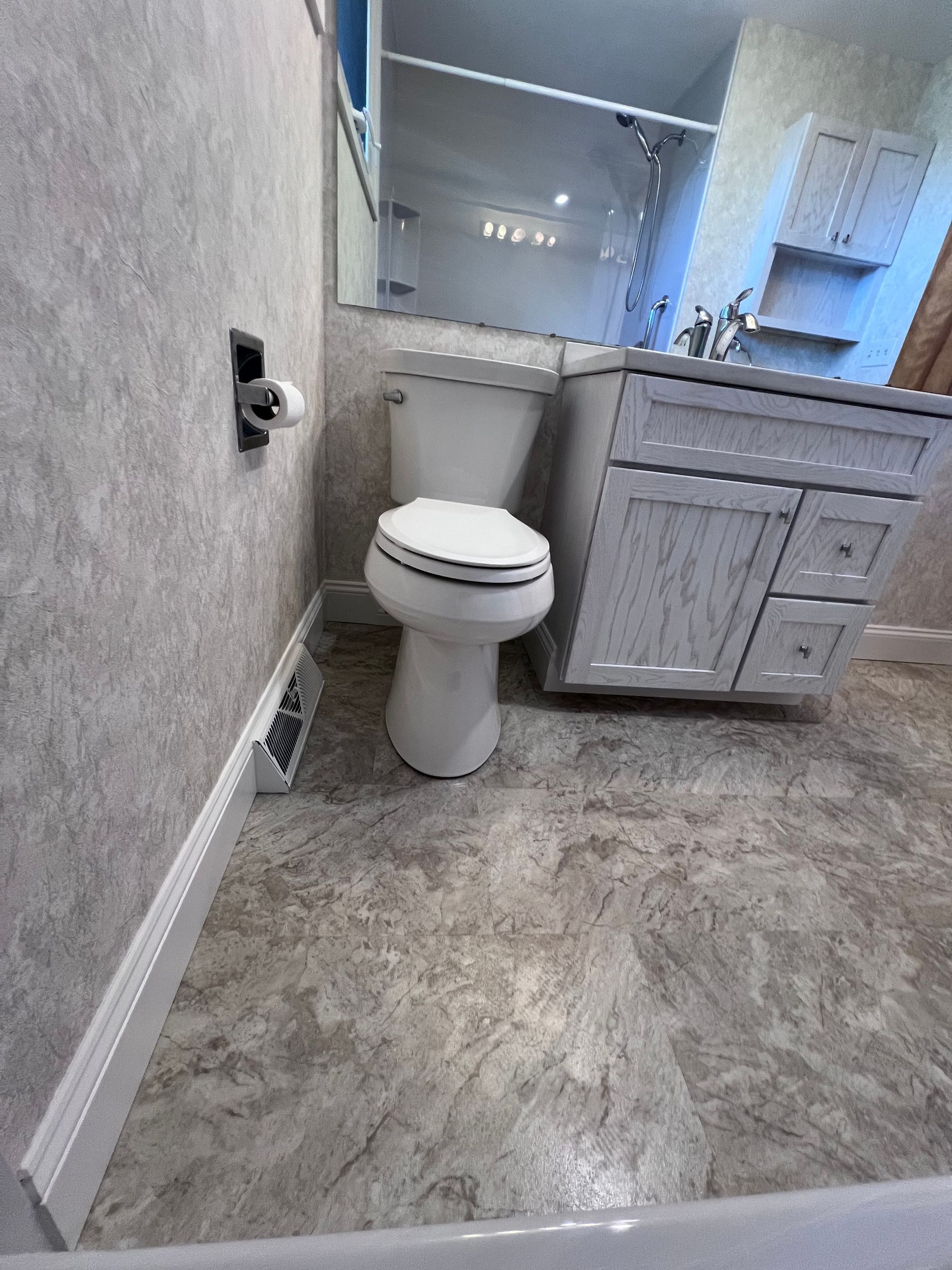 Small bathroom with toilet, vanity, gray walls, and patterned tile floor