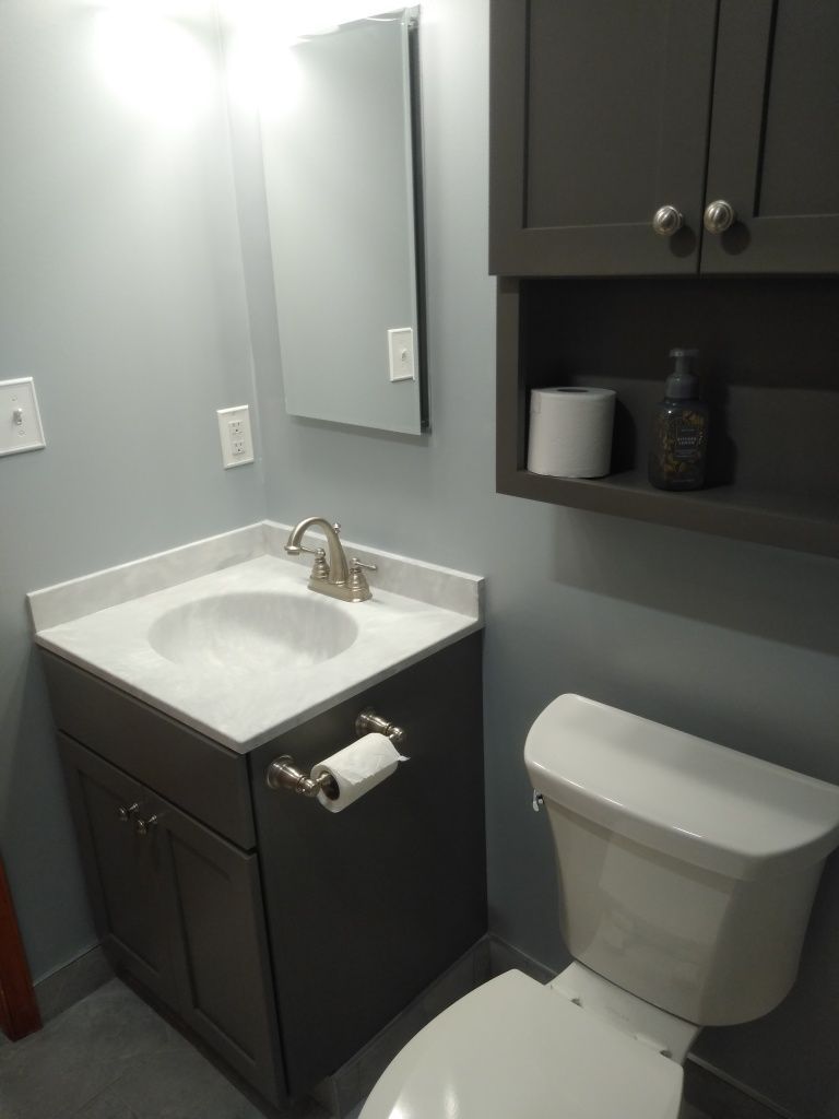 Small bathroom with dark cabinets, white sink and toilet, mirror, and wall cabinet.