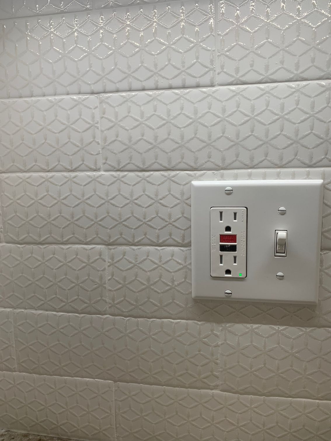 White wall with a light switch panel and outlet cover.