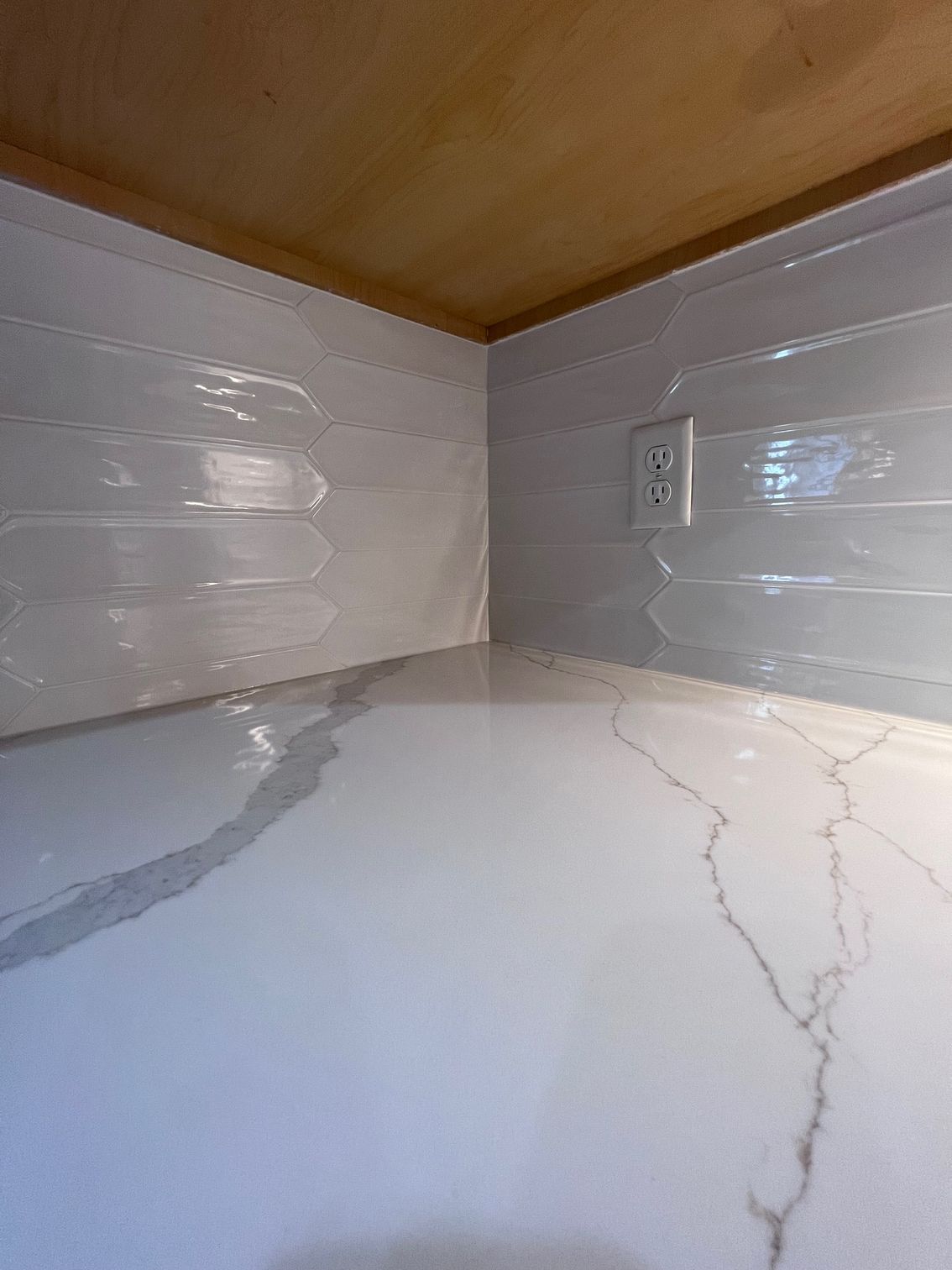 Kitchen countertop corner with white tile backsplash, wood ceiling, and marble-look surface with visible crack lines