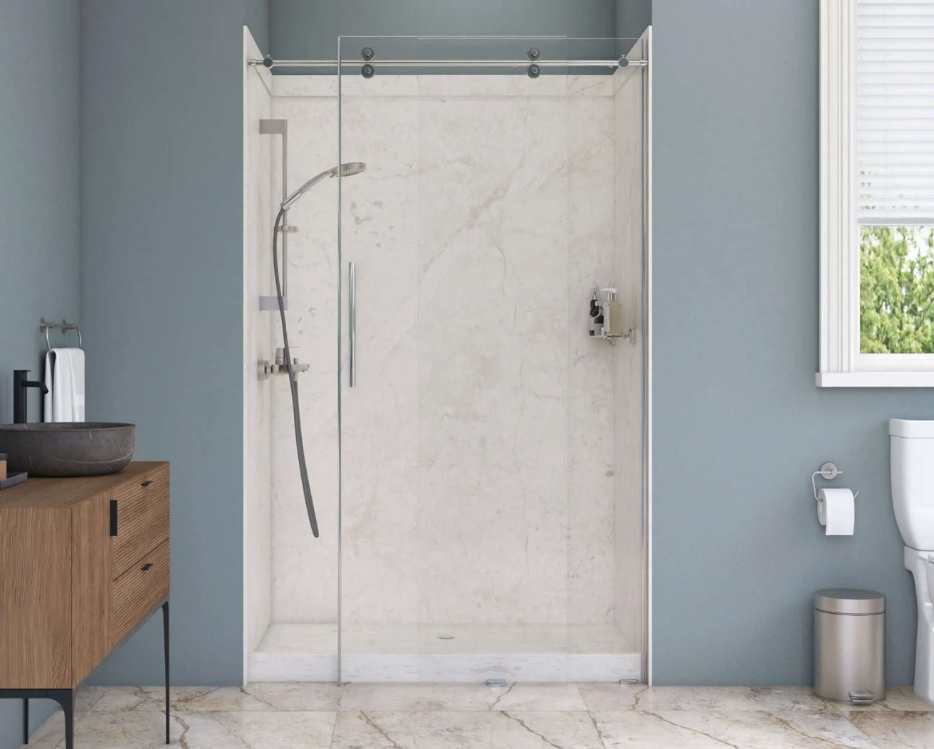 Modern bathroom with glass shower door, marble tile, blue walls, and a vanity on the left.