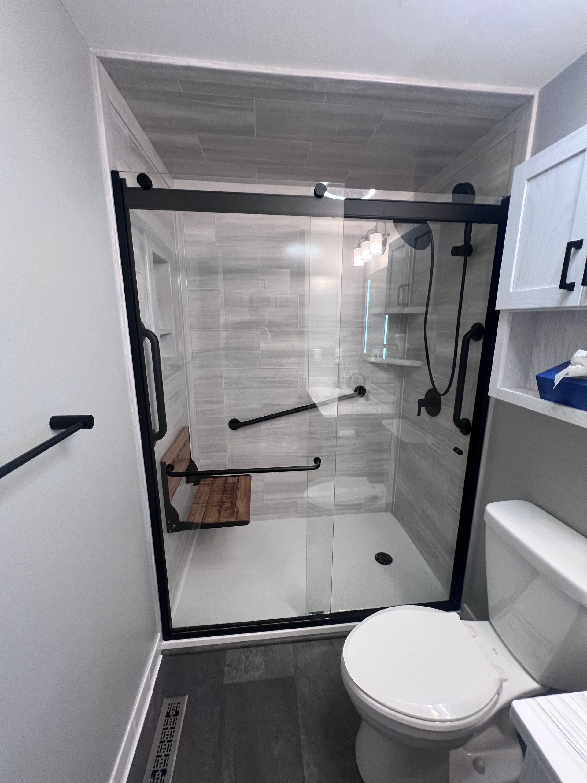 Modern bathroom with walk-in glass shower, white toilet, and built-in shelving