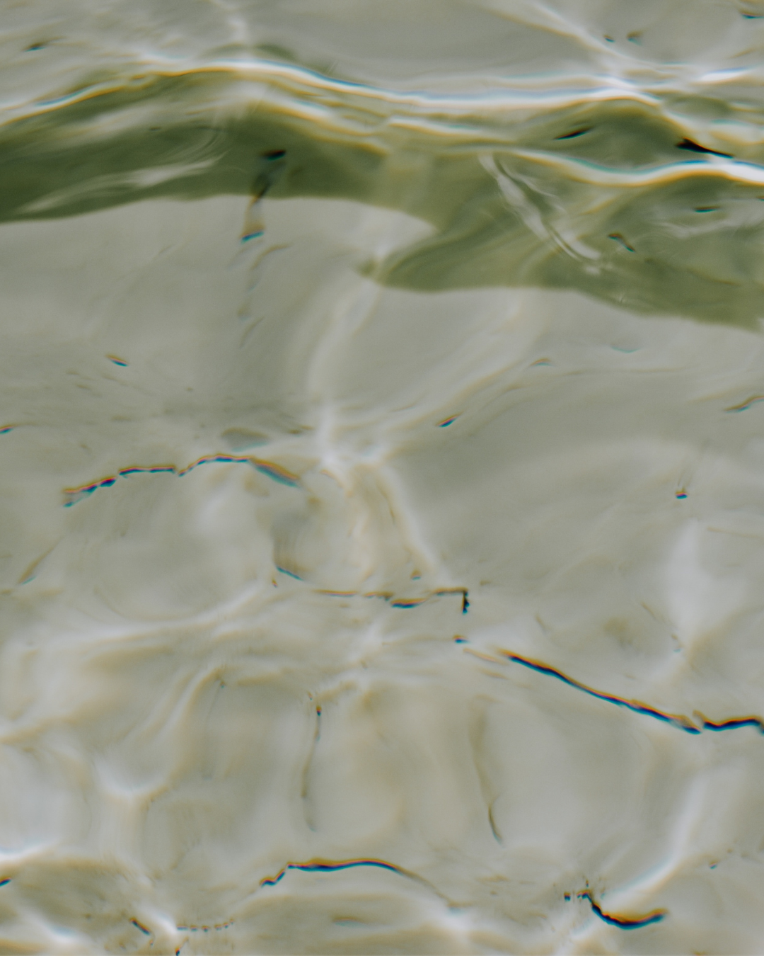 Close-up of gently rippling pale green water with sunlight reflections