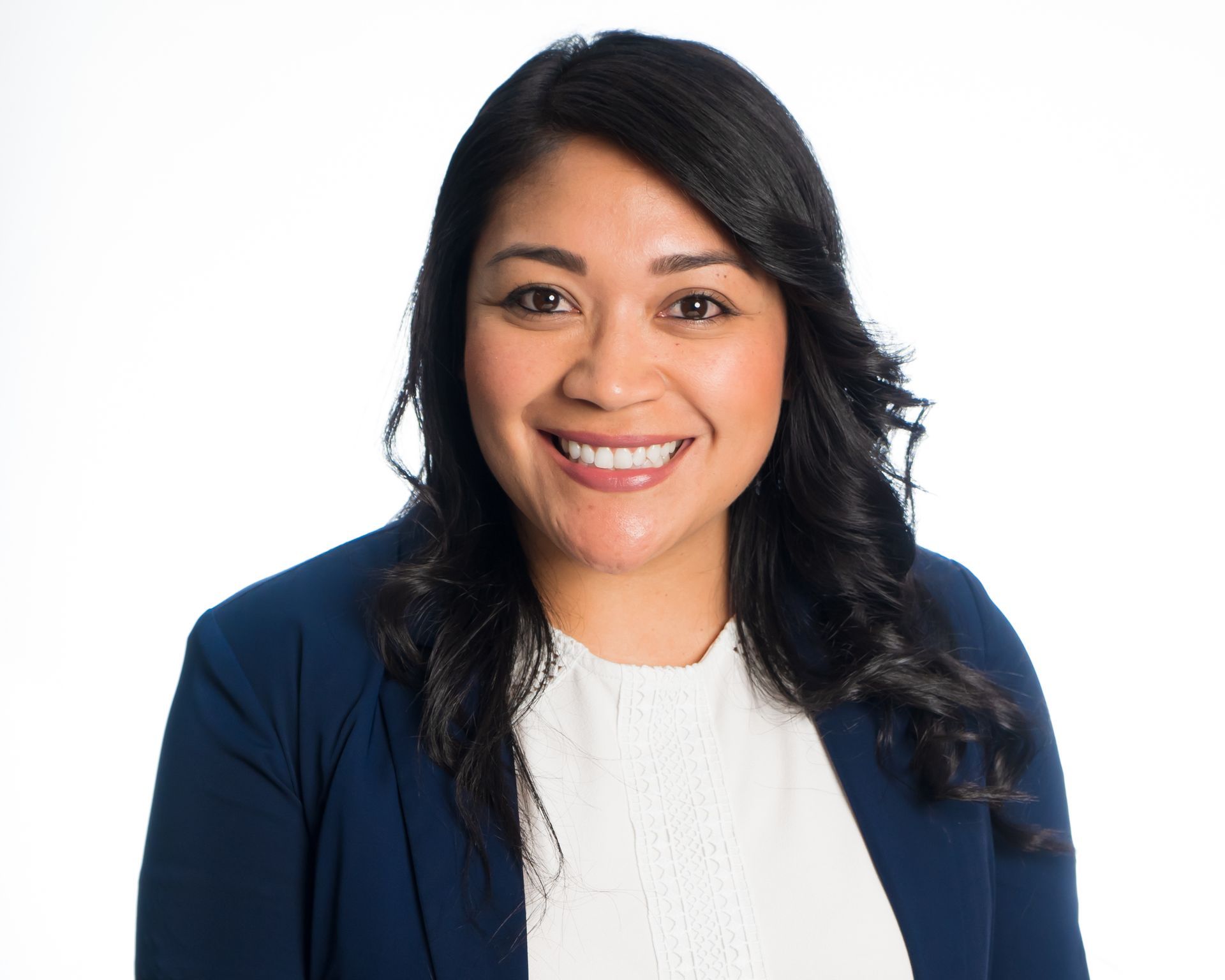 Smiling woman in a navy blazer and white top against a white background