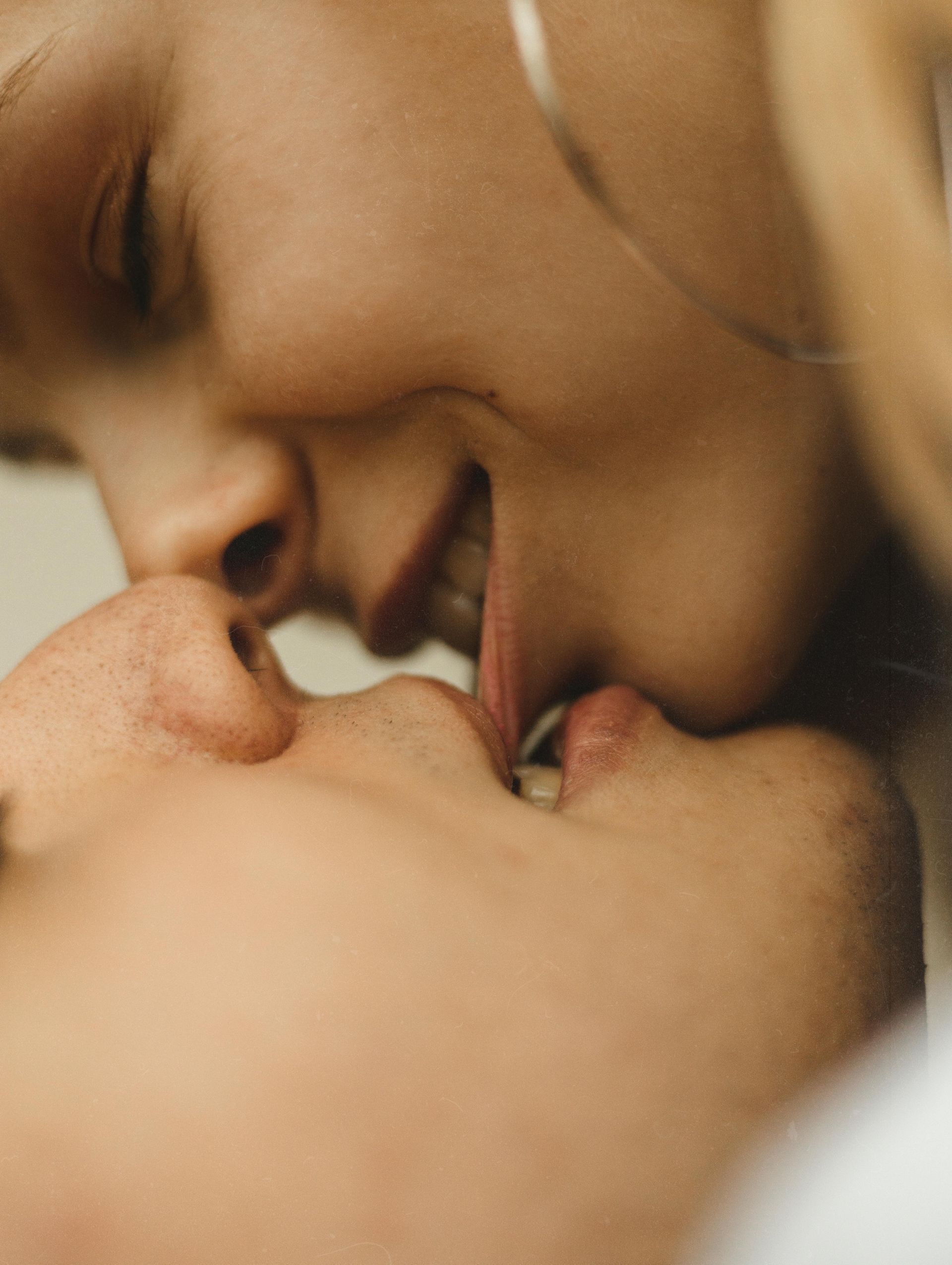 Two people lying close together, smiling softly as they touch noses.