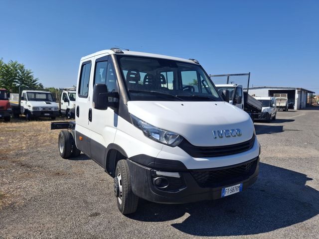 Un camion Iveco bianco con cabina e telaio, parcheggiato su un piazzale ghiaioso sotto un cielo azzurro e limpido.
