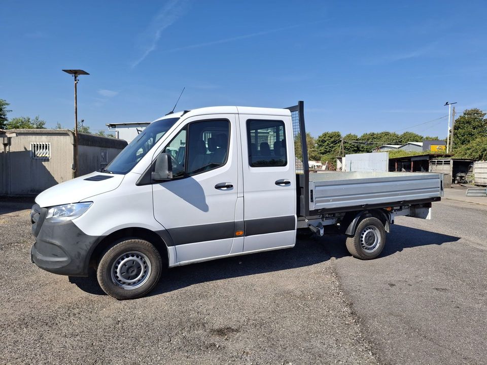 Un pick-up bianco con pianale ribassato parcheggiato su ghiaia sotto un cielo azzurro e limpido.