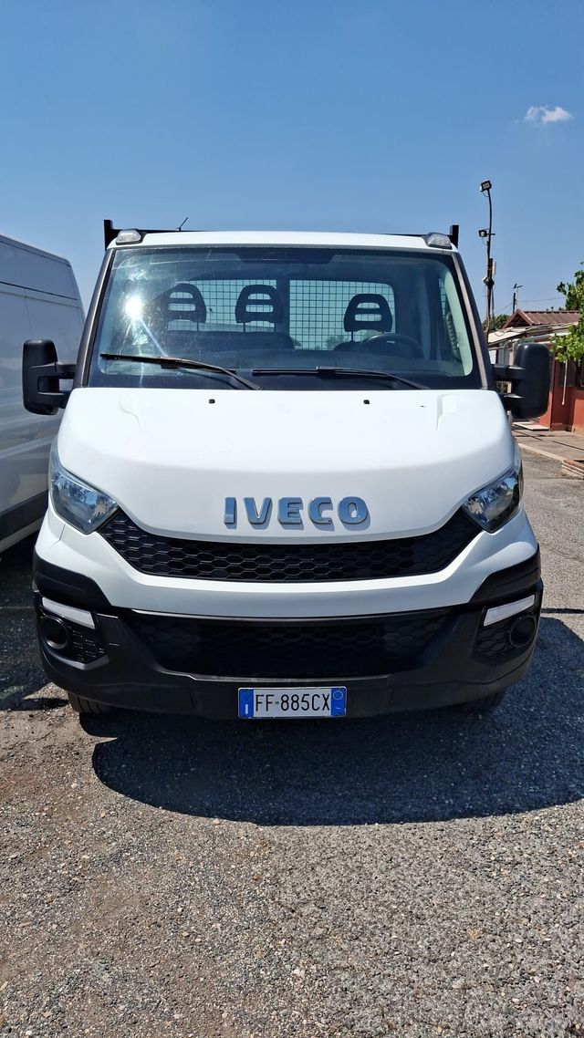 Vista frontale di un furgone Iveco bianco parcheggiato su un piazzale ghiaioso sotto un cielo azzurro e limpido.