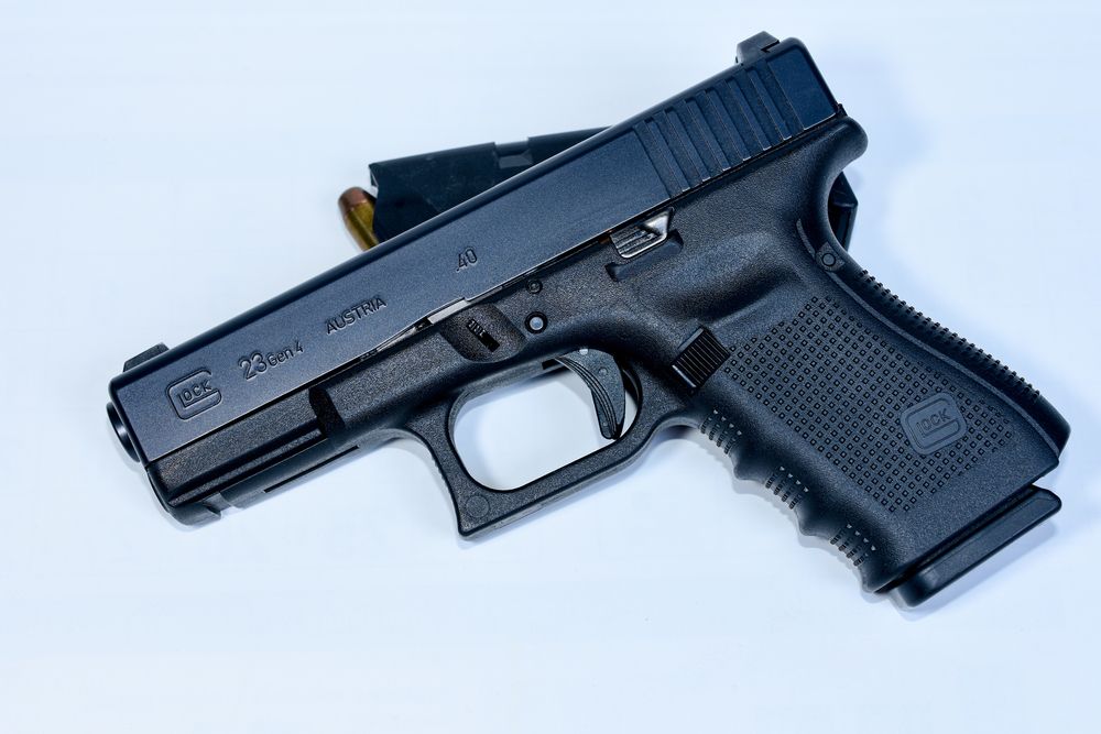 Black Glock 19 handgun with a magazine on a white surface.