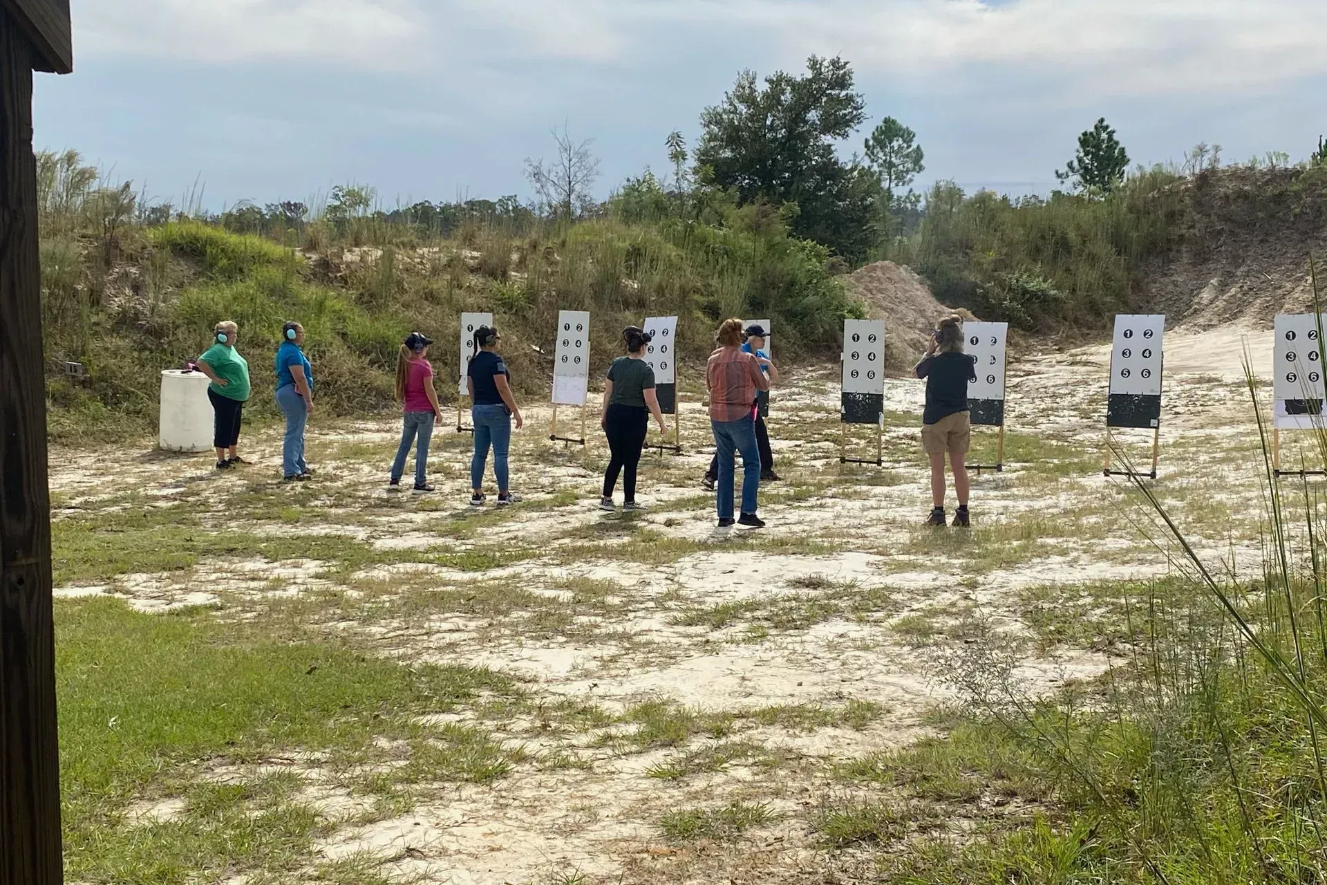 People at an outdoor shooting range, targets in front.