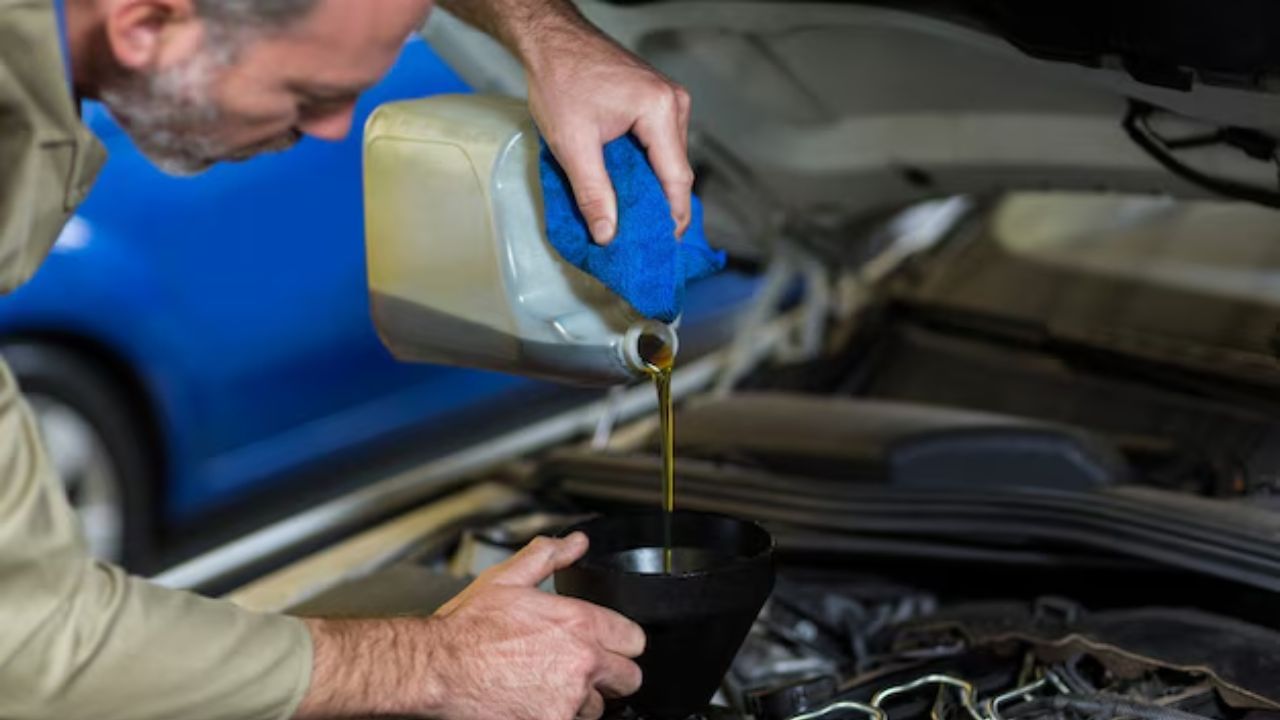 A professional mechanic pouring oil in a car’s engine