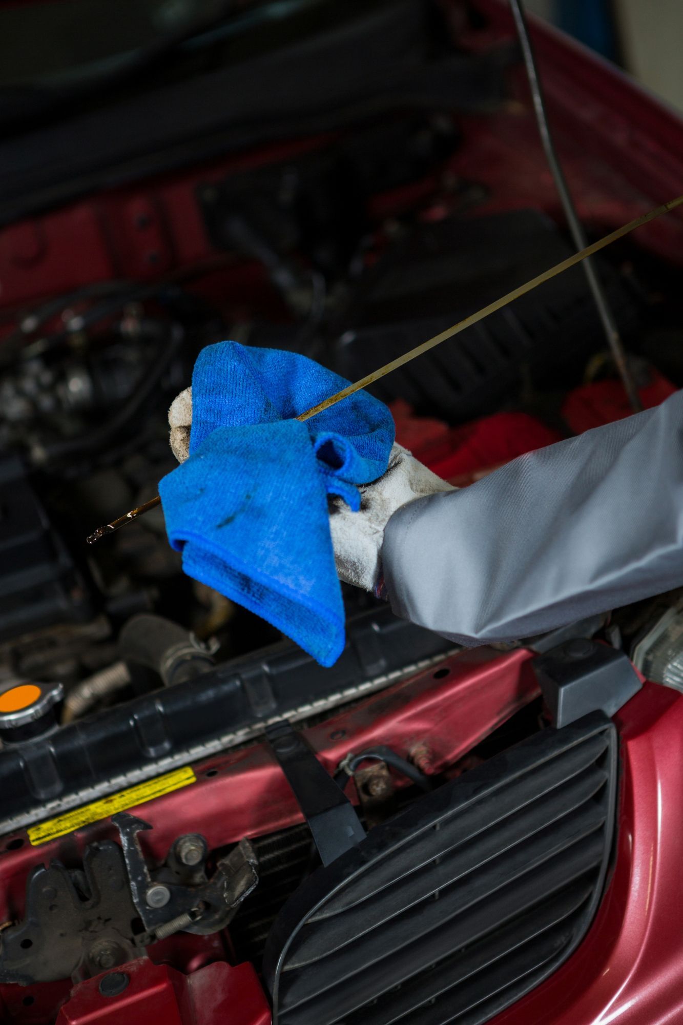 Automotive professional inspecting the engine oil level using a dipstick during routine vehicle maintenance