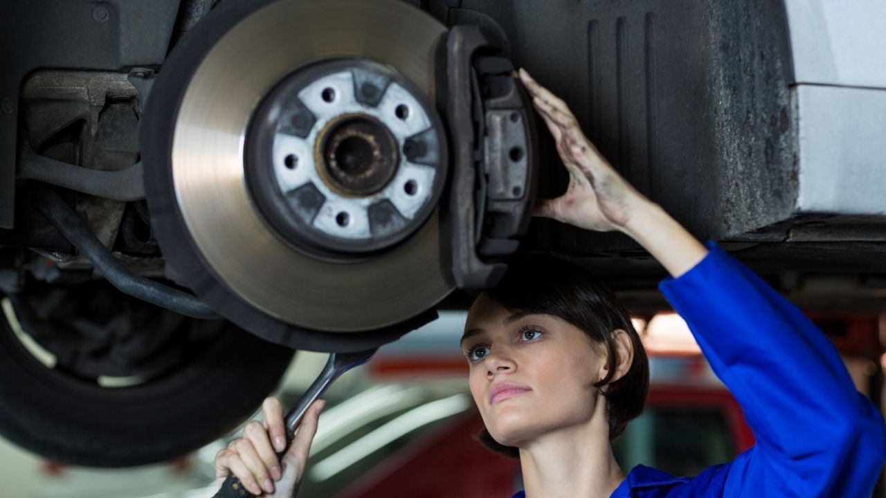 Auto mechanic inspecting a car’s brake rotor and caliper in a repair shop