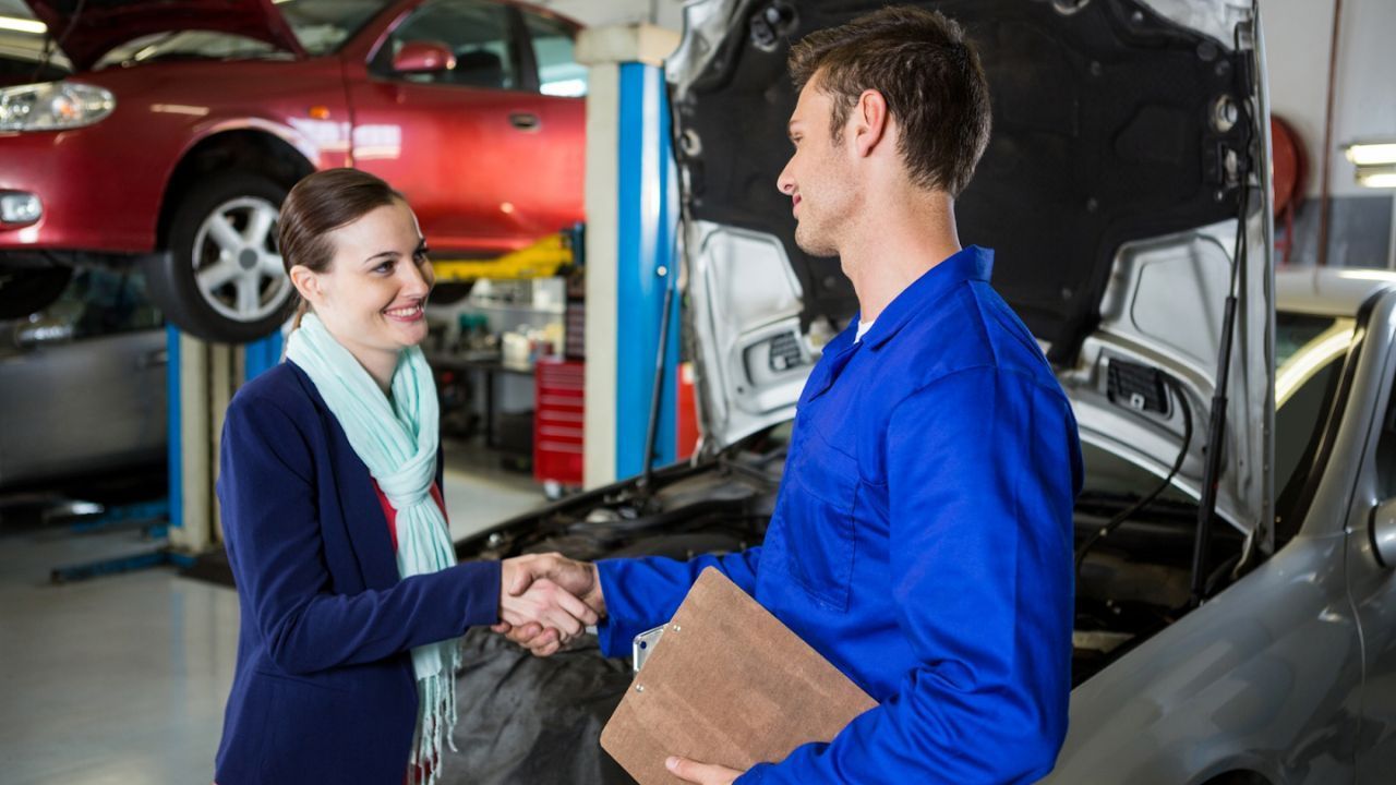 Customer shaking hands with a mechanic after a car repair service.
