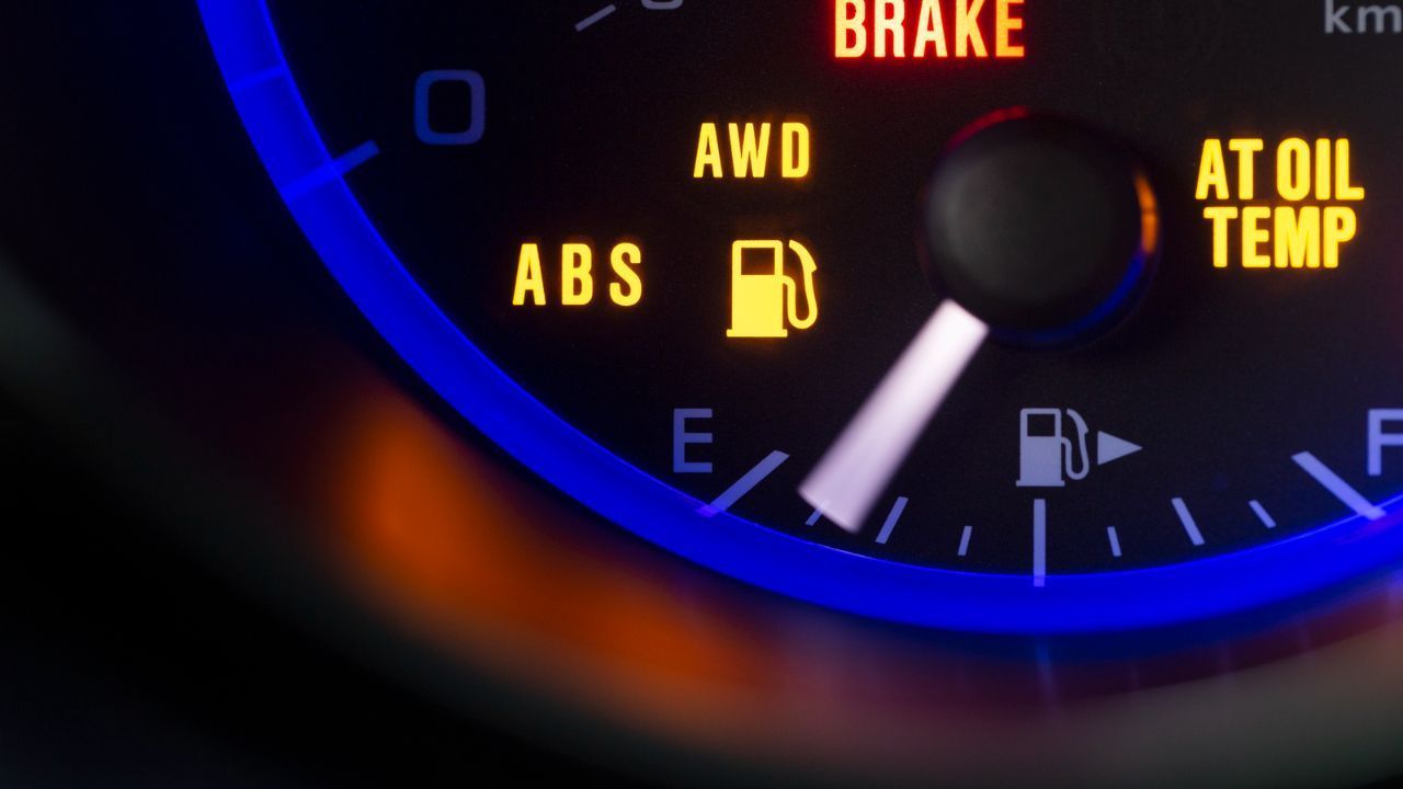 Illuminated car dashboard warning lights including low fuel and ABS
